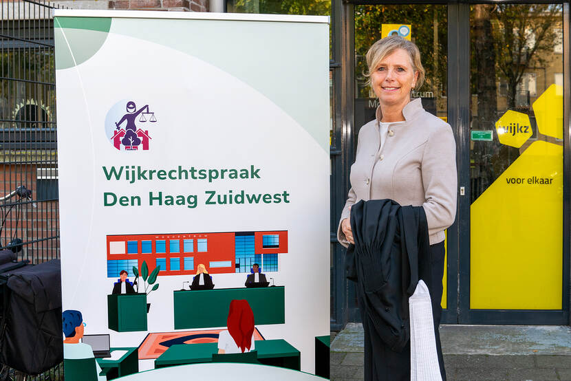 Robin de Lange naast de banner Wijkrechtspraak Den Haag Zuidwest